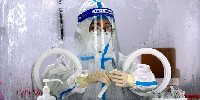 A worker wearing a protective suit waits to administer a COVID-19 test at a coronavirus testing site in Beijing, Wednesday, July 6, 2022. Residents of parts of Shanghai and Beijing have been ordered to undergo further rounds of COVID-19 testing following the discovery of new cases in the two cities, while additional restrictions remain in place in Hong Kong, Macao and other cities. 