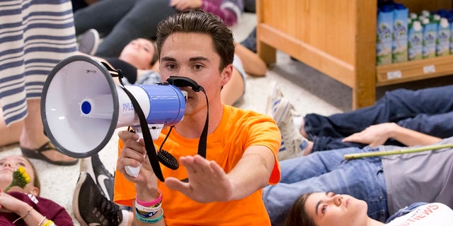 Marjorie Stoneman Douglas High School student David Hogg speaks as demonstrators lie on the floor at a Publix Supermarket in Coral Springs, Fla., May 25, 2018. 