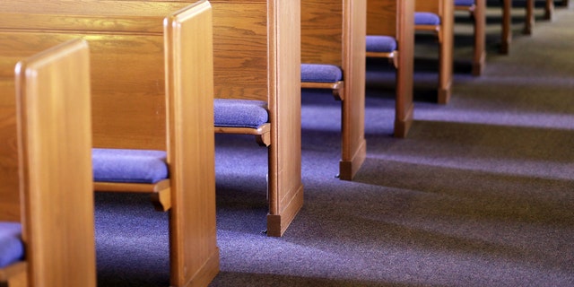 Window light is shing on rows of empty church pews in a Church Sanctuary without any people in it.