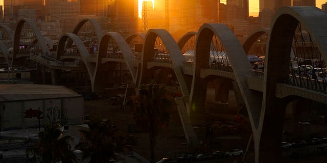 The sun sets behind the Los Angeles skyline during the opening ceremonies of the Sixth Street Bridge, a viaduct that connects the downtown Arts District with the historic Boyle Heights neighborhood. 