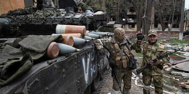 Russian soldiers pose by a T-80 tank in a position close to the Azovstal front line in the besieged port city of Mariupol.