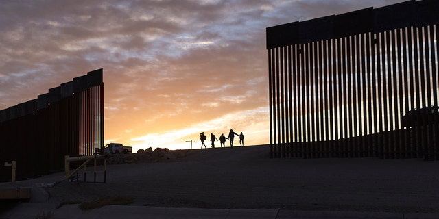 In this June 10, 2021, file photo, a pair of migrant families from Brazil pass through a gap in the border wall to reach the United States after crossing from Mexico to Yuma, Ariz., to seek asylum. 