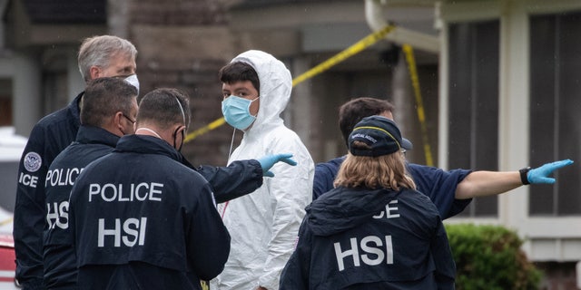 Homeland Security Investigations (HSI) personnel surround a man as he exits from a residence in southwest Houston, Texas, U.S., April 30, 2021. Police responding to reports of a kidnapping said they had found more than 90 people crammed into a two-story suburban Houston home and suspected it was being used in a human smuggling operation.  