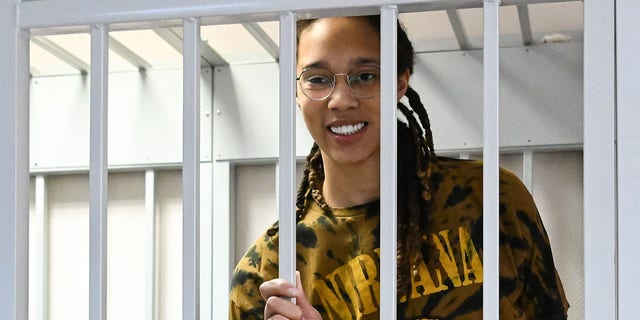 US WNBA basketball superstar Brittney Griner smiles inside a defendants' cage during a hearing at the Khimki Court in the town of Khimki outside Moscow on July 15, 2022. - Griner, a two-time Olympic gold medallist and WNBA champion, was detained at Moscow airport in February on charges of carrying in her luggage vape cartridges with cannabis oil, which could carry a 10-year prison sentence. 