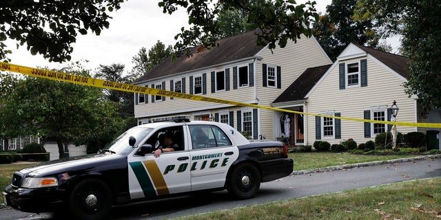 In this Sept. 29, 2014, file photo, a Montgomery Township Police officer sits in front of the partially burned home of John and Joyce Sheridan in Montgomery Township, N.J. 