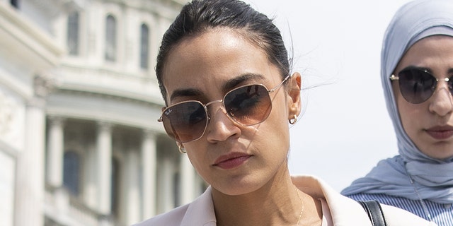 Rep. Alexandria Ocasio-Cortez, D-N.Y., talks with a reporter as she walks down the House steps 