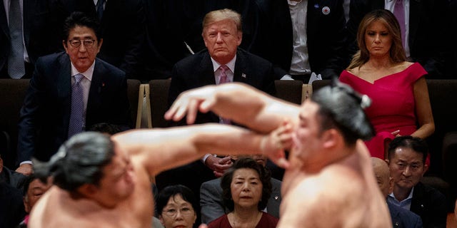 FILE - President Donald Trump attends the Tokyo Grand Sumo Tournament with Japanese Prime Minister Shinzo Abe at Ryogoku Kokugikan Stadium, Sunday, May 26, 2019, in Tokyo. First lady Melania Trump is at top right. (AP Photo/Evan Vucci)