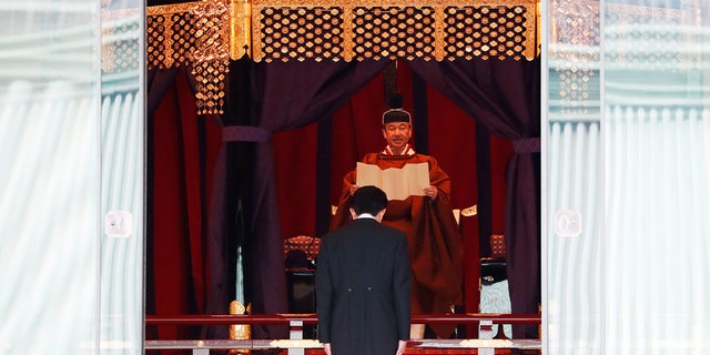 Japan's Emperor Naruhito speaks as Prime Minister Shinzo Abe bows during a ceremony to proclaim his enthronement to the world, called Sokuirei-Seiden-no-gi, at the Imperial Palace in Tokyo, Japan, Tuesday, Oct. 22, 2019. (Issei Kato/Pool Photo via AP)