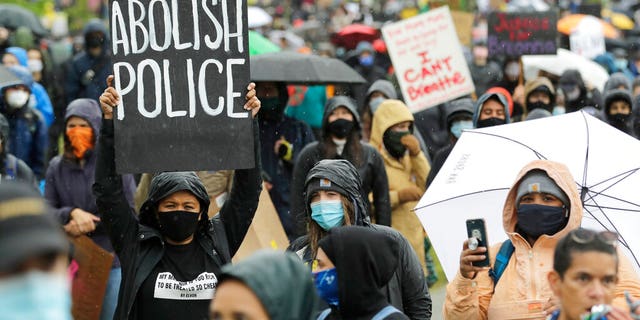  A protester holds a sign that reads "Abolish Police" during a "Silent March" against racial inequality and police brutality that was organized by Black Lives Matter Seattle-King County, Friday, June 12, 2020, in Seattle.  (AP Photo/Ted S. Warren)