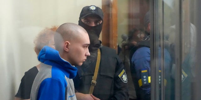 Russian army Sergeant Vadim Shishimarin, 21, is seen behind a glass during a court hearing in Kyiv, Ukraine, Friday, May 13, 2022. The trial of a Russian soldier accused of killing a Ukrainian civilian opened Friday, the first war crimes trial since Moscow's invasion of its neighbor. (AP Photo/Efrem Lukatsky)