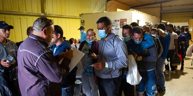 People line up for a commercial bus that will take them to the San Antonio airport at a warehouse run by the Mission: Border Hope nonprofit group run by the United Methodist Church in Eagle Pass, Texas, May 23, 2022. 