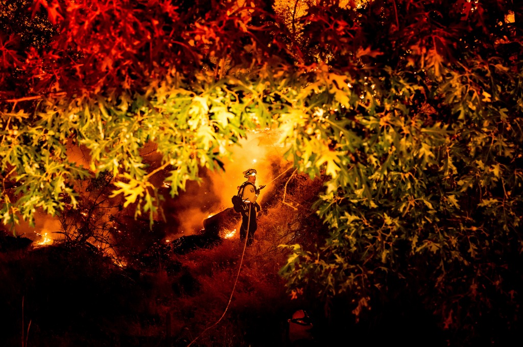 A firefighter sprays water on the Electra Fire burning in the Rich Gulch community of Calaveras County, Calif.