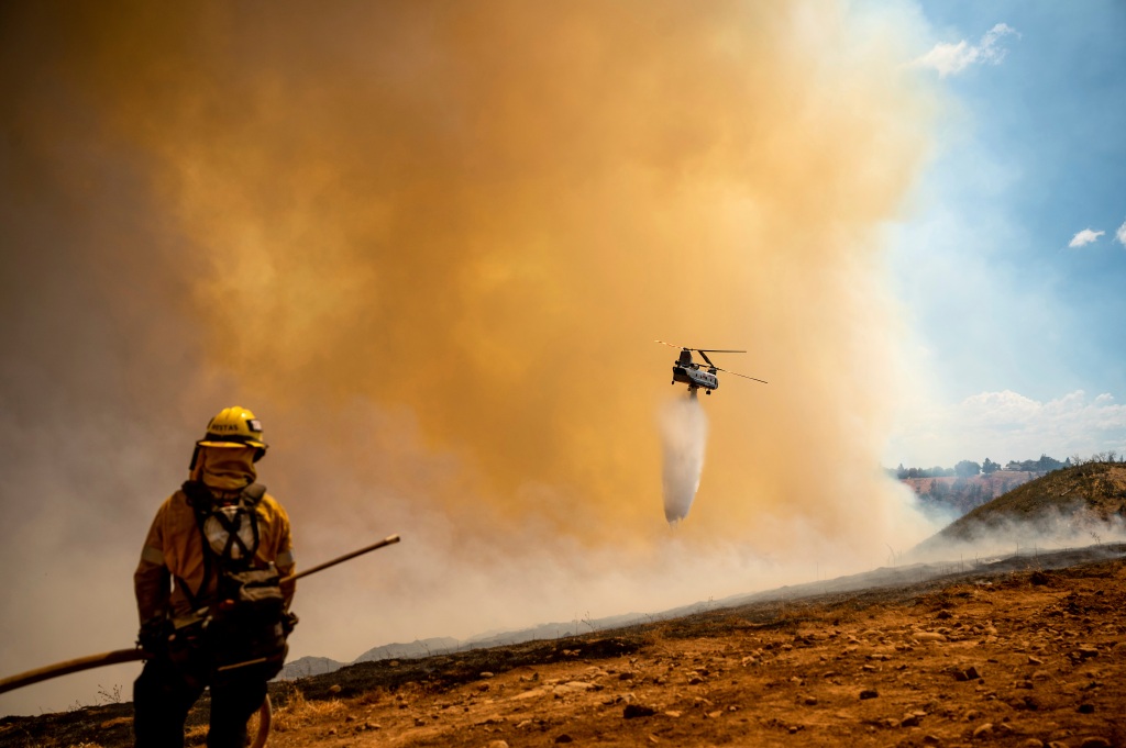 A helicopter drops water while battling the Electra Fire in the Pine Acres community of Amador County, Calif.