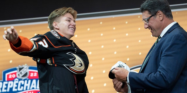 Pavel Mintyukov puts on an Anaheim Ducks jersey after being selected during nthe NHL hockey draft in Montreal on Thursday, July 7, 2022. 