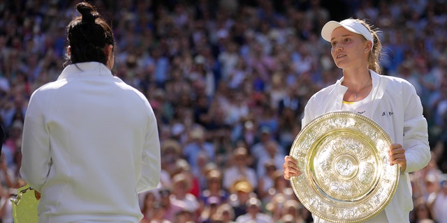 Kazakhstan's Elena Rybakina celebrates with the trophy after beating Tunisia's Ons Jabeur, left, to win the women's singles championship at Wimbledon in London Saturday, July 9, 2022. 