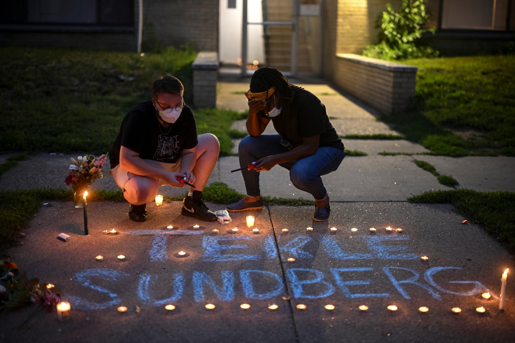 Marcia Howard, activist and George Floyd Square caretaker, right, takes a moment as she lights candles during a vigil for 20-year old Andrew Tekle Sundberg Thursday, July 14, 2022.