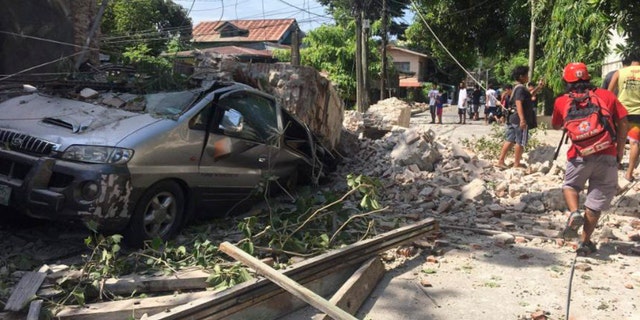 In this handout photo provided by the Philippine Red Cross, a vehicle is damaged as a wall collapses after a strong earthquake hit Ilocos Sur province, Philippines on Wednesday, July 27, 2022.