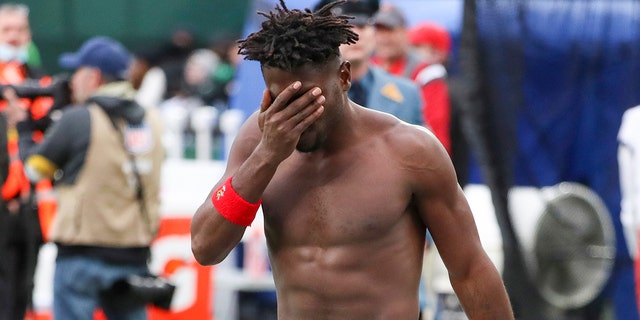 Tampa Bay Buccaneers wide receiver Antonio Brown wipes his face as he leaves the field after throwing his equipment into the stands while his team is on offense during the third quarter of an NFL game against the New York Jets, Jan. 2, 2022, in East Rutherford, New Jersey.