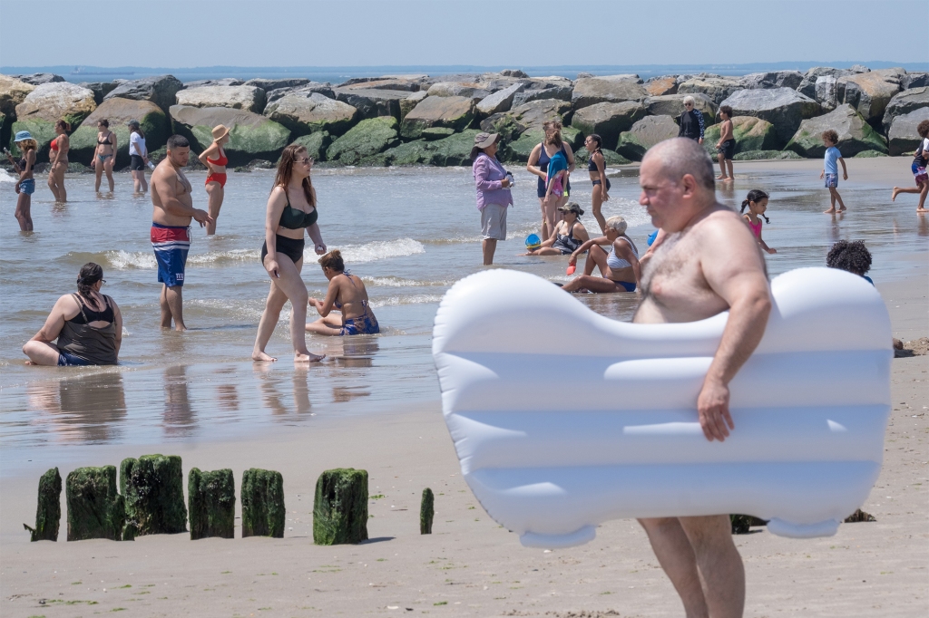 Beach goers stand along the shore.