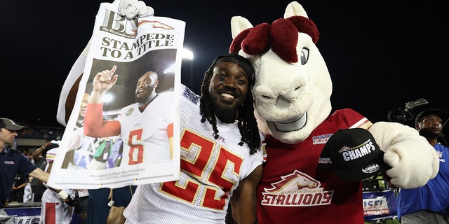 Bo Scarbrough #25 of the Birmingham Stallions poses with the Birmingham Stallions mascot after defeating the Philadelphia Stars 33-30 to win the USFL Championship game at Tom Benson Hall Of Fame Stadium on July 03, 2022 in Canton, Ohio.