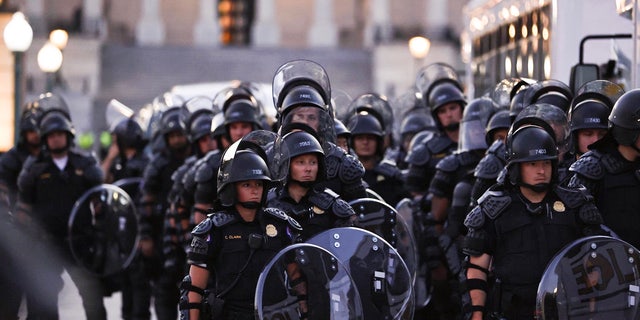 Capitol Police stand dressed in riot gear as protestors gather near the Supreme Court in response to the ruling on Roe v. Wade.