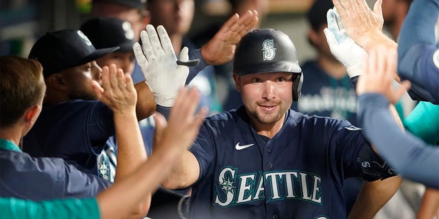 Seattle Mariners' Cal Raleigh is greeted in the dugout after he hit a solo home run against the Texas Rangers during the seventh inning of a baseball game, Tuesday, July 26, 2022, in Seattle. 