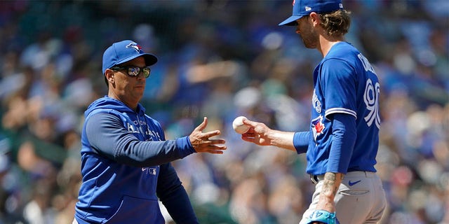 Toronto Blue Jays pitcher Adam Cimber, right, is pulled by manager Charlie Montoyo, left, during the eighth inning of a baseball game against the Seattle Mariners, Sunday, July 10, 2022, in Seattle. The Mariners won 6-5. 