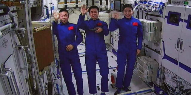 In this photo released by Xinhua News Agency, an image taken off the screen at the Beijing Aerospace Control Center shows Chinese astronauts from left, Cai Xuzhe, Chen Dong and Liu Yang wave from inside the Wentian lab module on Monday, July 25, 2022. China added the laboratory to its permanent orbiting space station Monday as it moves toward completing the structure in coming months. (Guo Zhongzheng/Xinhua via AP)