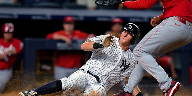 New York Yankees' DJ LeMahieu slides past Cincinnati Reds pitcher Alexis Diaz to score on a wild pitch during the 10th inning of a baseball game Wednesday, July 13, 2022, in New York. The Yankees won 7-6. 