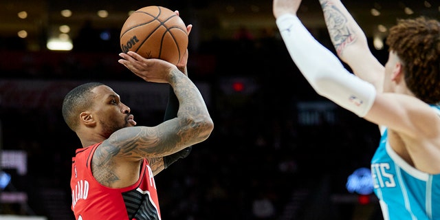 Portland Trail Blazers guard Damian Lillard, left, shoots over Charlotte Hornets guard LaMelo Ball during the second half of a game in Portland, Oregon, on Dec. 17, 2021.