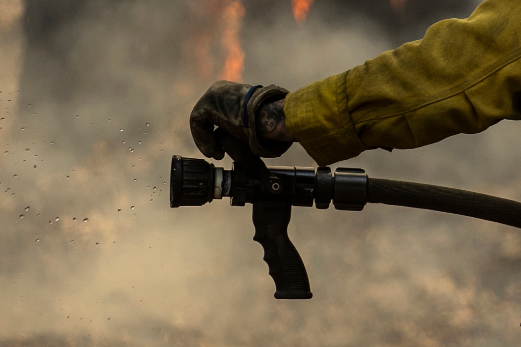 Water is seen from a hose as a CalFire firefighter monitors a backfiring operation against the Washburn Fire in Yosemite National Park, Calif. Monday, July 11, 2022. 