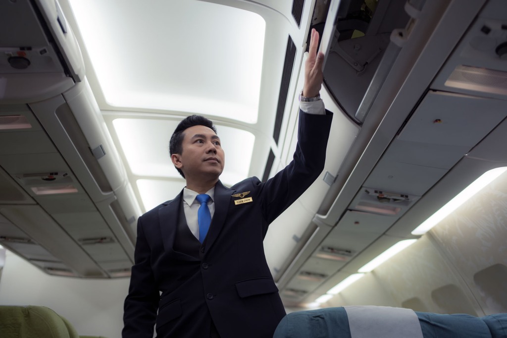 Flight attendant checking over head.
