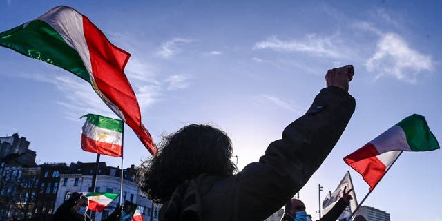 People gesture and wave former flags of Iran as they protest outside the Antwerp criminal court during the trial of four persons including an Iranian diplomate and Belgian-Iranian couple in Antwerp, on February 4, 2021. 