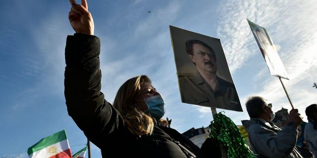 People wave former flags of Iran and hold portraits as they protest outside the Antwerp courthouse, on February 4, 2021, during the trial of four suspects including an Iranian diplomat accused of taking part in a plot to bomb an opposition rally in France. 