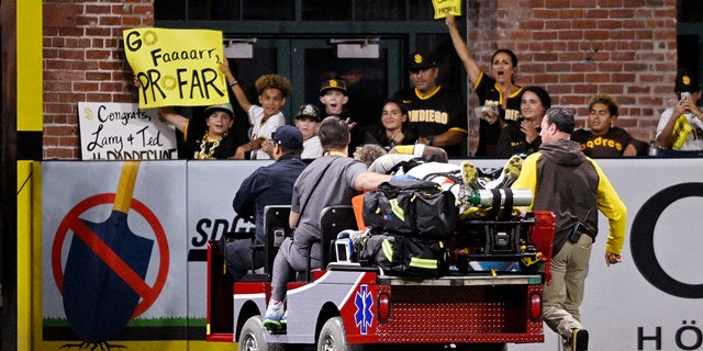 Fans hold up signs as Jurickson Profar, #10 of the San Diego Padres, is taken away in a cart during the fifth inning of a baseball game against the San Francisco Giants July 7, 2022 at Petco Park in San Diego, California. Profar was injured during a collision with C.J. Abrams, #77 of the San Diego Padres. 