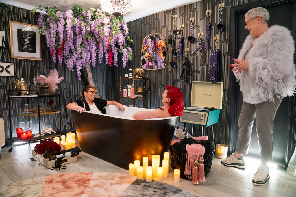 Melanie Rose (far right) with her clients Brodie and Bettie in their new sex room. She stands smiling while they sit in a bathtub. 