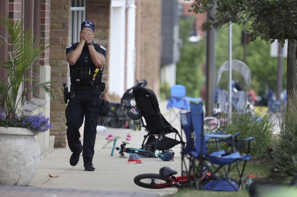 A Lake County, Illinois, police officer walks down Central Avenue in Highland Park on July 4 after a shooter fired on the northern suburb.