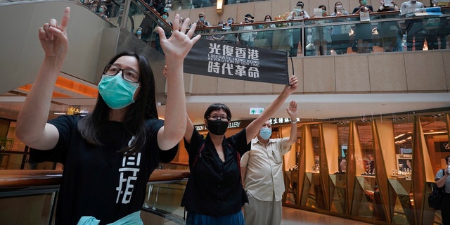 Protesters show a banner "Librate Hong Kong, Revolution of our time" in a shopping mall during a protest in Hong Kong in June. The slogan had just been banned by the government under the new legislation, stating that it had separatist connotations. (AP)