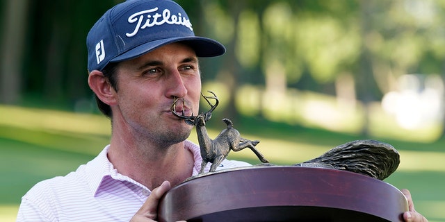 J.T. Poston kisses the trophy after winning the John Deere Classic golf tournament, Sunday, July 3, 2022, at TPC Deere Run in Silvis, Ill. 