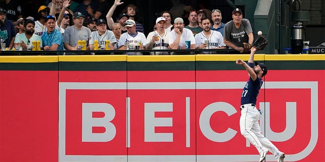 Seattle Mariners left fielder Jesse Winker makes a leaping catch of a fly ball hit by Texas Rangers' Corey Seager during the sixth inning of a baseball game, Tuesday, July 26, 2022, in Seattle. 