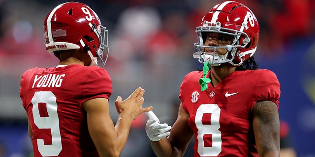 Bryce Young (9) of the Alabama Crimson Tide talks with teammate John Metchie III (8) before the SEC Championship game against the Georgia Bulldogs at Mercedes-Benz Stadium Dec. 4, 2021, in Atlanta.