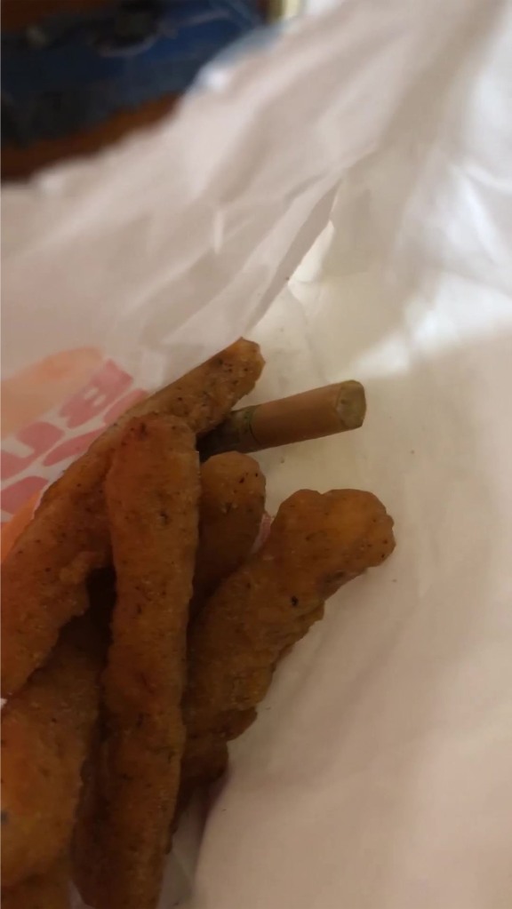 The half-smoked cigarette was nestled amongst the chicken sticks.