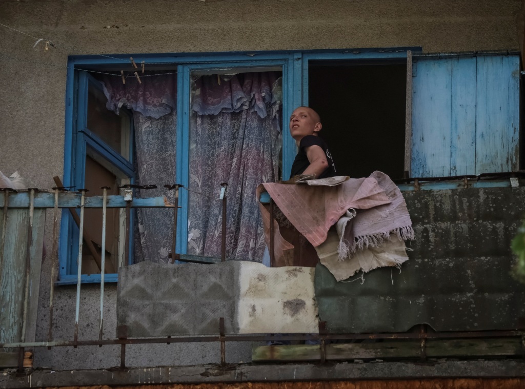 A local resident looks out a window in a building damaged by a Russian military strike in Kramatorsk, Ukraine on July 19, 2022. 