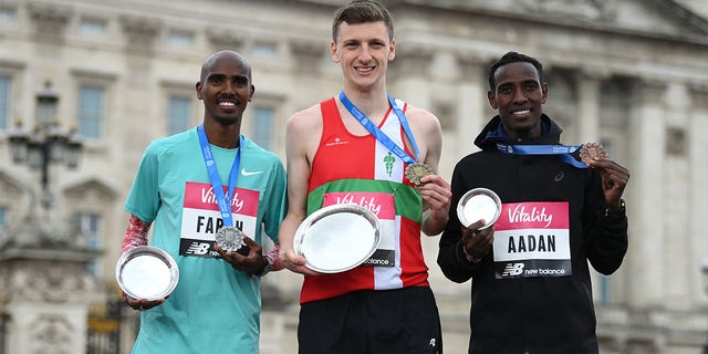 Gold Medallist, Ellis Cross, Silver Medallist, Mo Farah and Bronze Medallist, Mohamud Aadan pose on the podium after the men's elite race ahead of Mo Farah during the Vitality London 10,000m road race on May 02, 2022 in London, England.