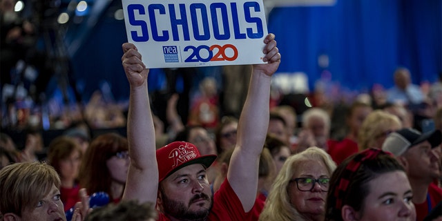 An man holds a sign during the National Education Association #StrongPublicSchools Presidential Forum.