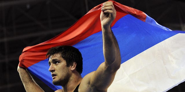 Russia's Shirvani Muradov celebrates with his national flag afte rwinning the gold medal at the men's freestyle 96kg final wrestling match against Kazakhstan's Taimuraz Tigiyev on August 21, 2008 at the 2008 Beijing Olympic Games. 