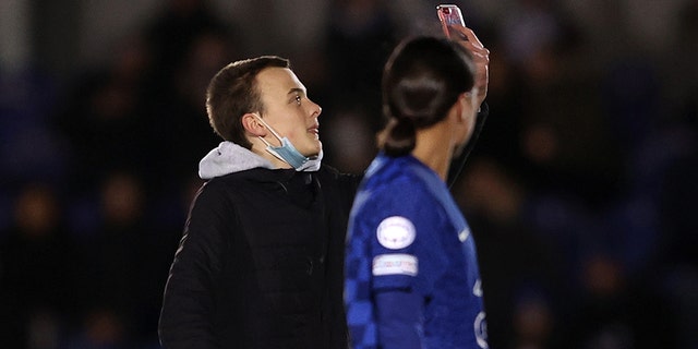 A pitch invader attempts to get a selfie with Sam Kerr of Chelsea  during the UEFA Women's Champions League group A match between Chelsea FC and Juventus at Kingsmeadow on December 08, 2021 in Kingston upon Thames, England.