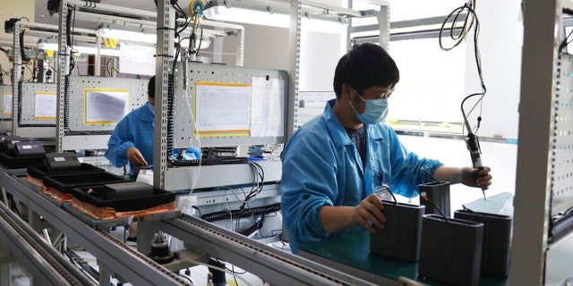 In this photo released by Xinhua News Agency, a staff members wearing masks work at a workshop in an industry park in Qingpu District of Shanghai, east China, May 17, 2022.