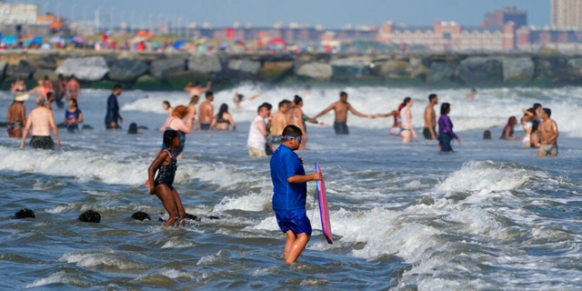 People enjoy the water at Rockaway Beach, Tuesday, July 19, 2022, in the Queens borough of New York. 