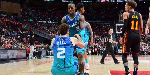 Terry Rozier #3 helps LaMelo Ball #2 of the Charlotte Hornets up during the game against the Atlanta Hawks during the 2022 Play-In Tournament on April 13, 2022 at State Farm Arena in Atlanta, Georgia. 